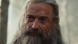 Hugh Jackman with grey wig and beard looking grizzled in A24's The Death Of Robin Hood. 