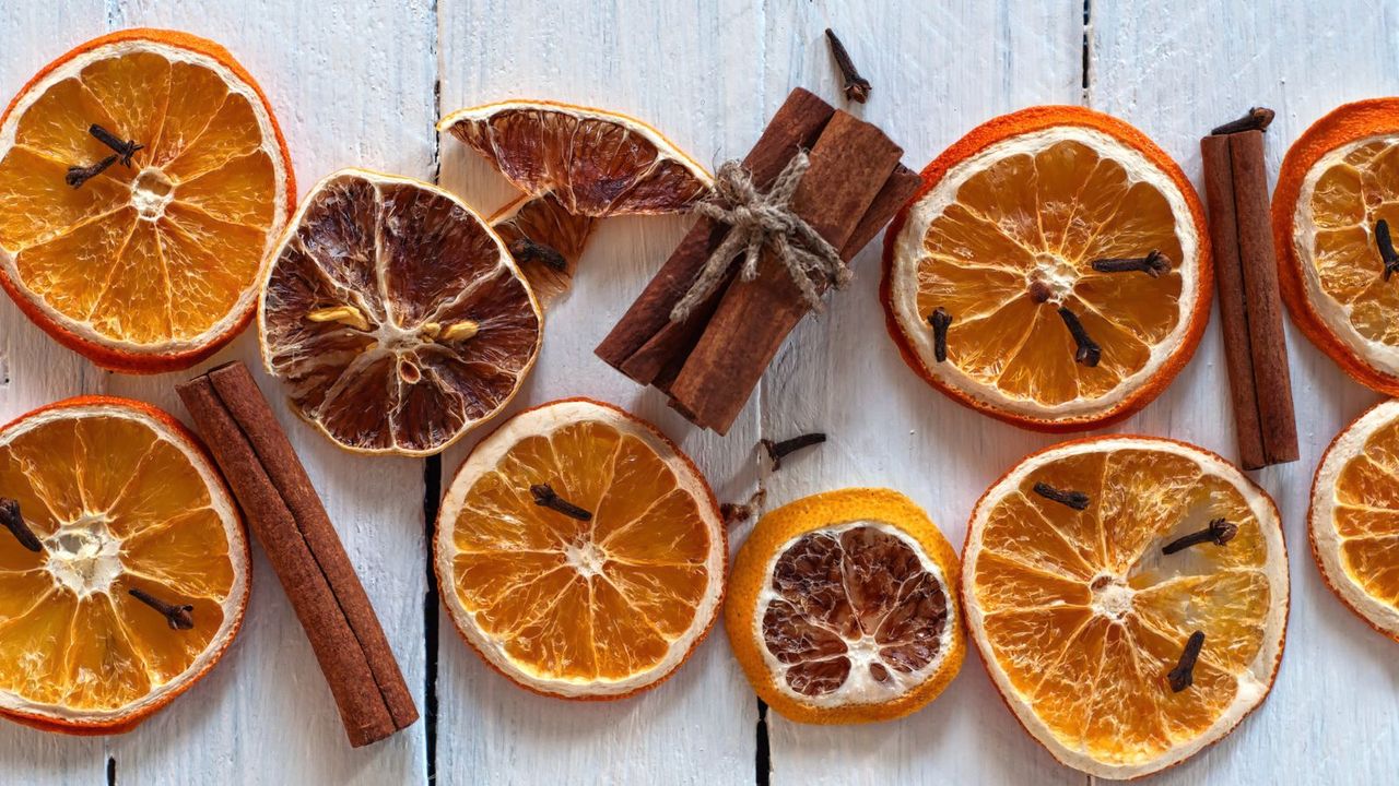 Dried slices of orange with cinnamon sticks on a white wooden table