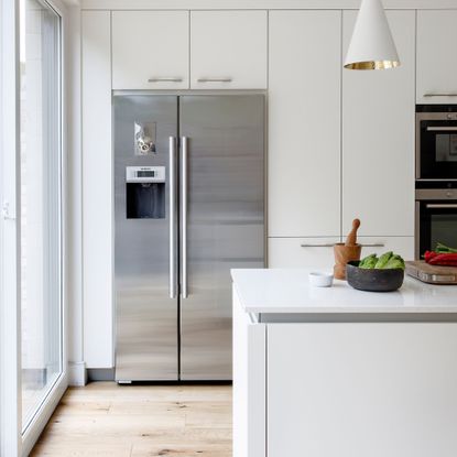 Silver fridge freezer in a white kitchen and standing on wooden floor