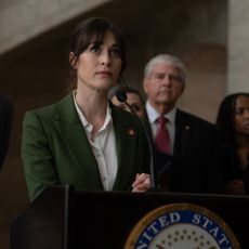 lizzy caplan as alexandra mullen speaking at a podium in the tv show zero day