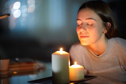 Woman smelling a lighted candle in the night