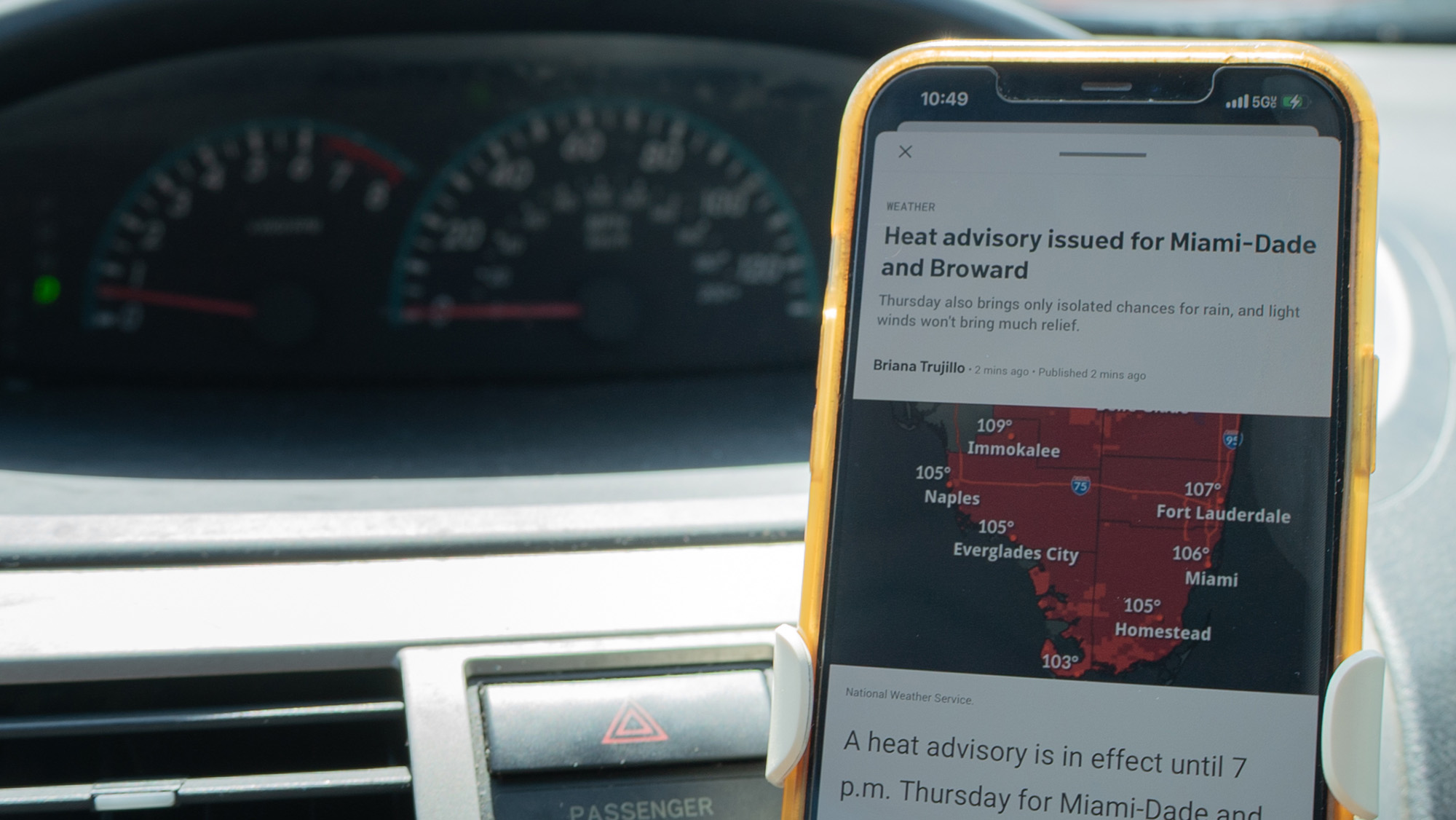 A phone sits in a car holder and shows a heat alert