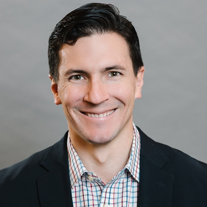 male with short dark hair, clean shaven wearing check shirt and navy blazer