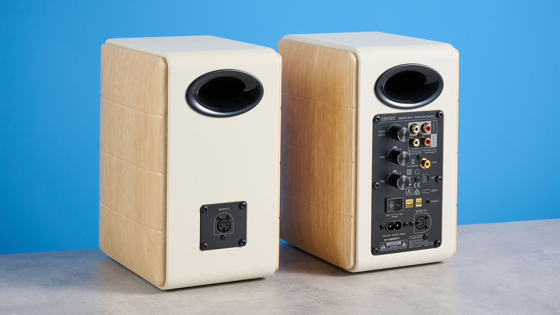 the edifier s880db mkii speakers in white and wood colorway showing the connectivity options, remote control, against a blue background