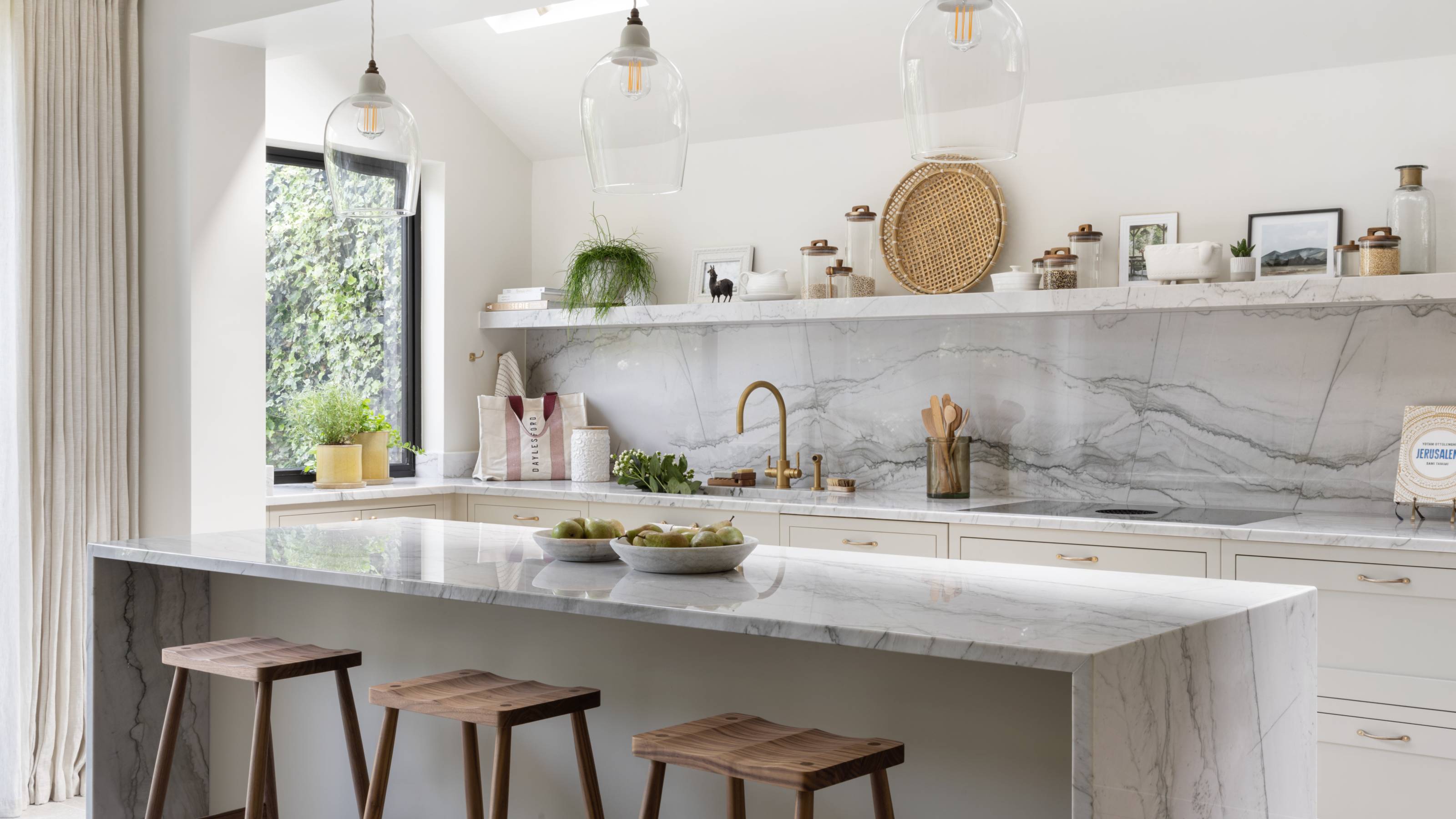 white kitchen with stone marble island, backsplash and shelving