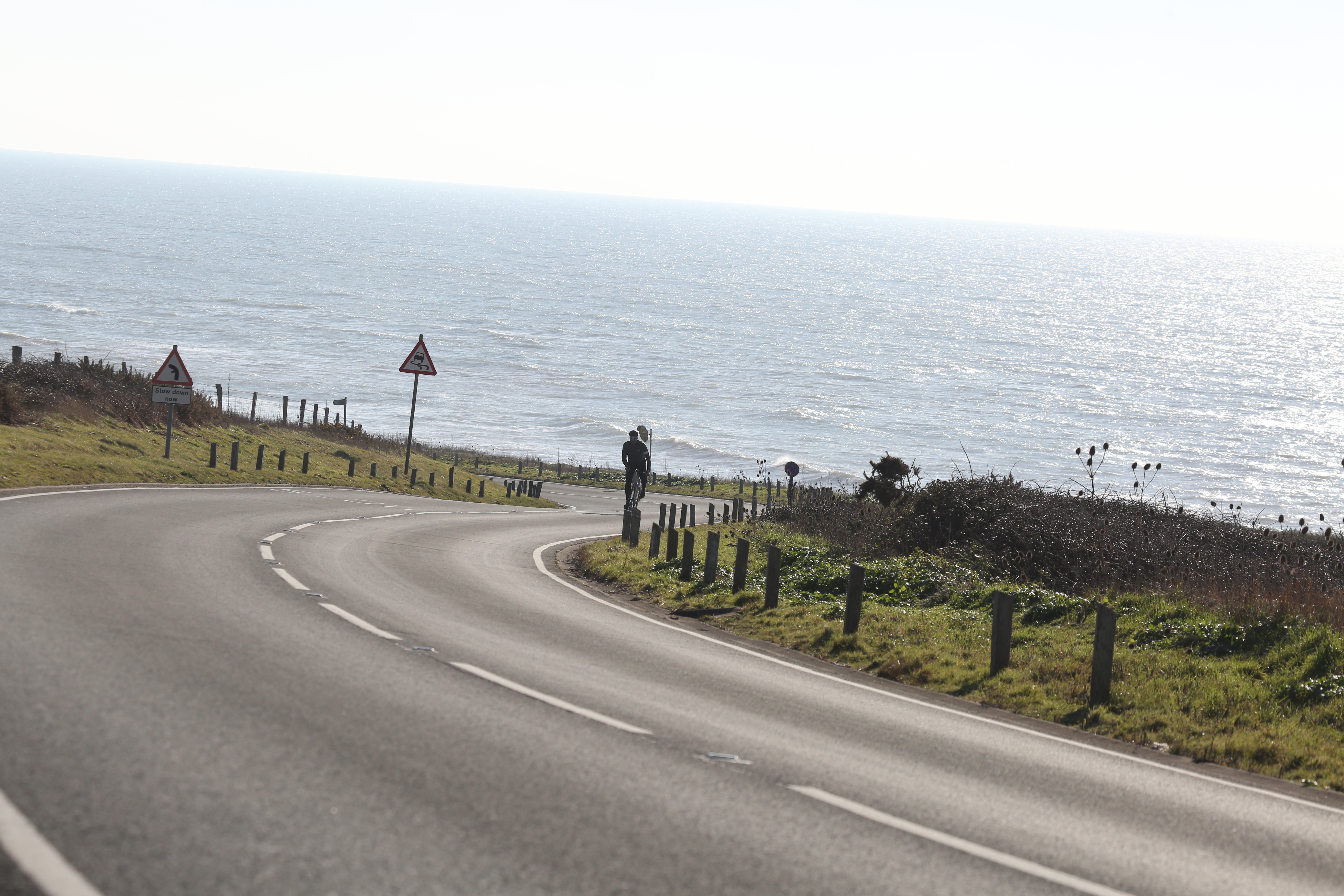Man cycles down hill towards the sea