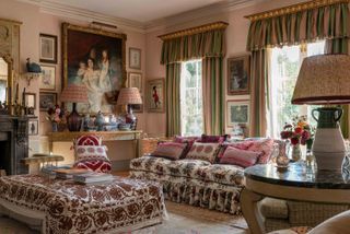 living room with floral sofa, curtains and valance, classic portraits, antique furniture and pink walls, opulant and traditional