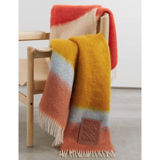 colorful striped loewe blanket draped over a chair