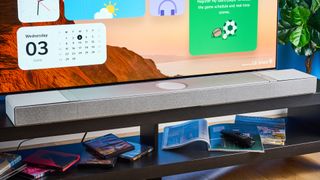 the KEF XIO soundbar in gray photographed with a TV and the Tom's Guide blue background