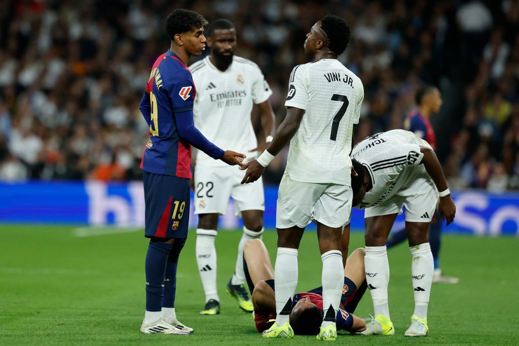 Barcelona&#039;s Spanish forward #19 Lamine Yamal (L) talks with Real Madrid&#039;s Brazilian forward #07 Vinicius Junior as Barcelona&#039;s Polish forward #09 Robert Lewandowski lies on the field during the Spanish league football match between Real Madrid CF and FC Barcelona at the Santiago Bernabeu stadium in Madrid on October 26, 2024. (Photo by OSCAR DEL POZO / AFP) (Photo by OSCAR DEL POZO/AFP via Getty Images)