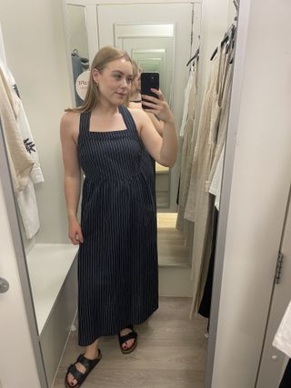 Woman in dressing room wears blue striped linen dress