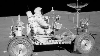 an astronaut in a space suit driving a car-like vehicle with no roof