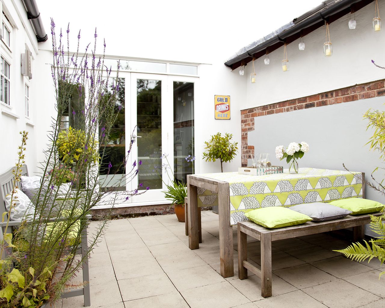 A small courtyard garden with bench and outdoor table with green tablecloth