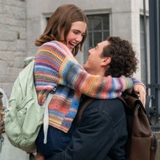 Ella Bright as Hannah Wells and Belmont Cameli as Garrett Graham as she leaps into his arms outside of a school building in the tv show adaptation of off campus