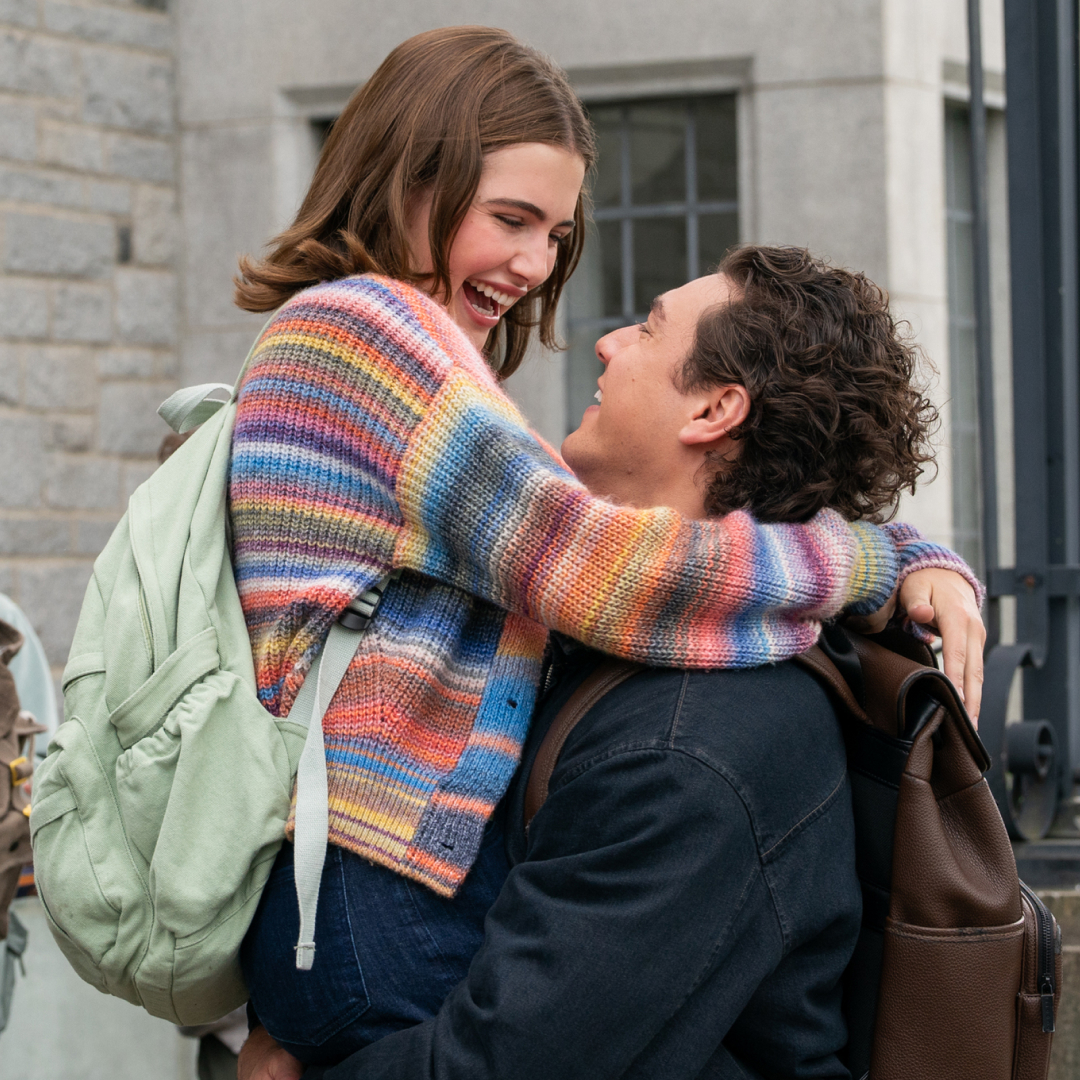 Ella Bright as Hannah Wells and Belmont Cameli as Garrett Graham as she leaps into his arms outside of a school building in the tv show adaptation of off campus