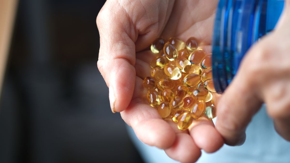 Close up on an older person&#039;s hands as they pour out a large quantity of soft gel vitamins into their palm