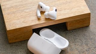 Bästa AirPods: Ett par Apple AirPods Pro ligger på en träplatta bredvid sitt tillhörande laddningsfodral på ett bord.