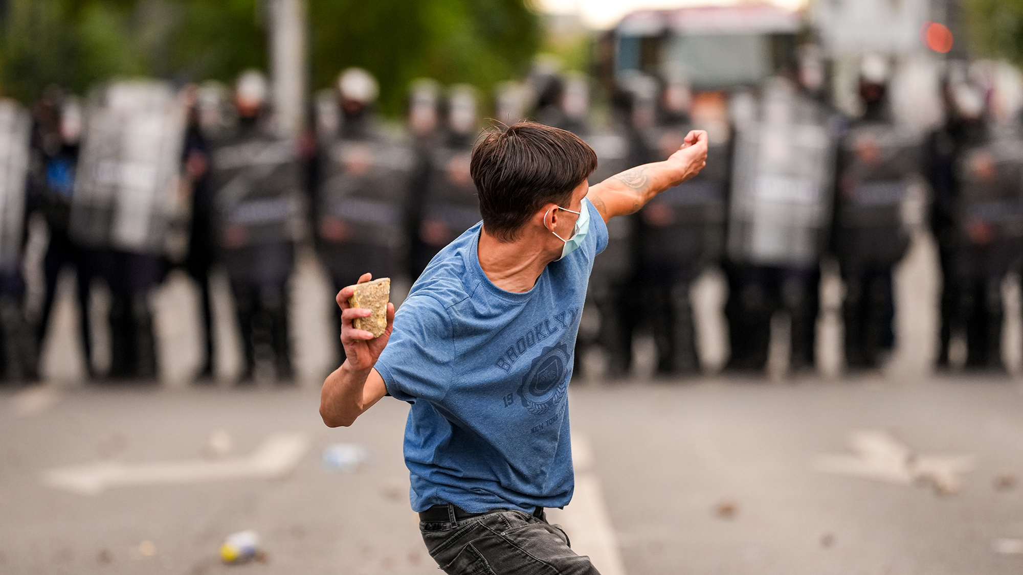 A demonstrator throws a rock towards a line of riot police during a farmers' protest in Bucharest, Romania