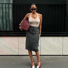 Fashion person Emily Nitta wears a cream halterneck top, a tailored skirt and two tone heel. She is carrying a matching burgundy duffle and oval sunglasses in a recent image from her Instagram.
