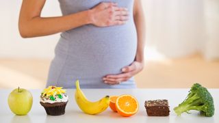 Pregnant woman standing behind row of food