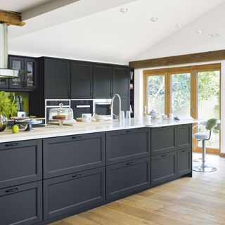 grey kitchen with drawers and cupboards on wooden floor next to wooden sliding door