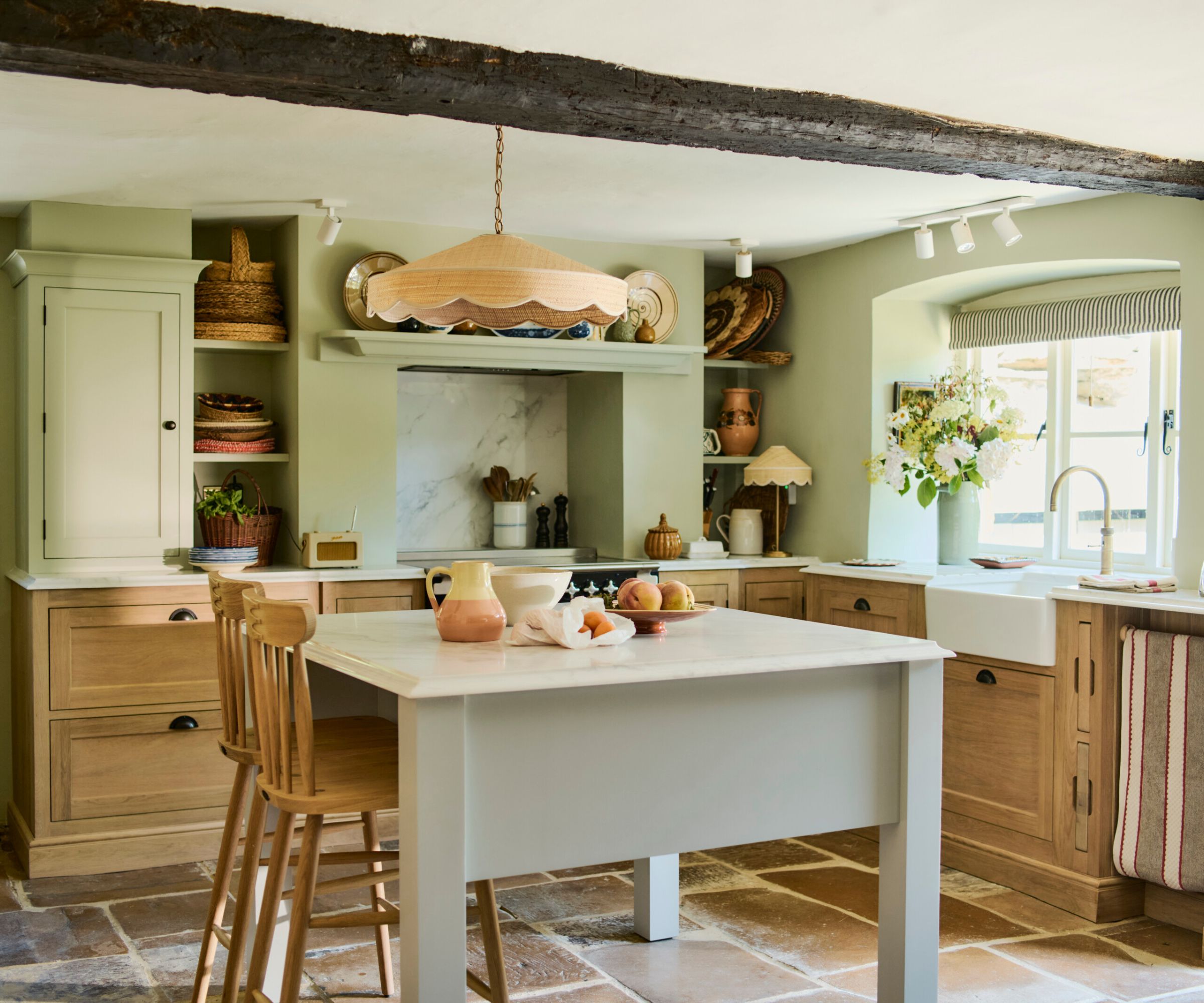 A country cottage kitchen with wooden L-shaped perimeter cabinets and a gray freestanding kitchen island with seating