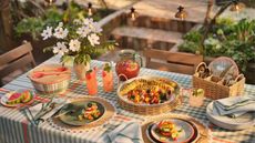outdoor patio table styled with new Hearth & Hand™ with Magnolia x Target collection pieces including plaid tablecloth, raffia placemats and rattan serveware