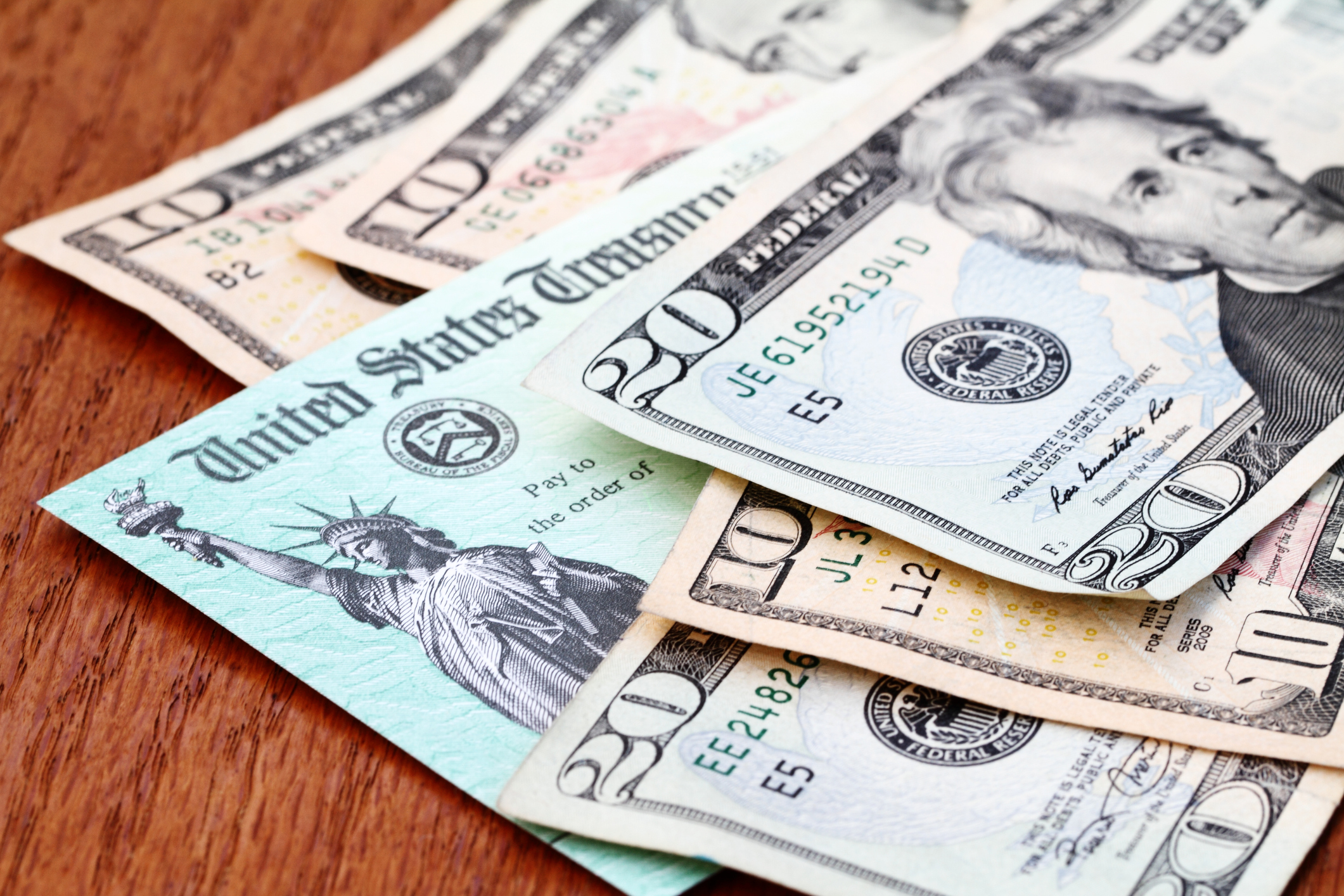 Cash and federal treasury check on wood countertop.