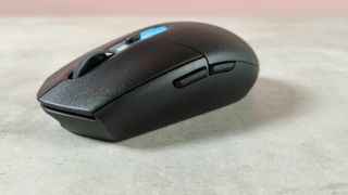 Three-quarter view of Logitech G305 X Superlight on desk with pink wall in background