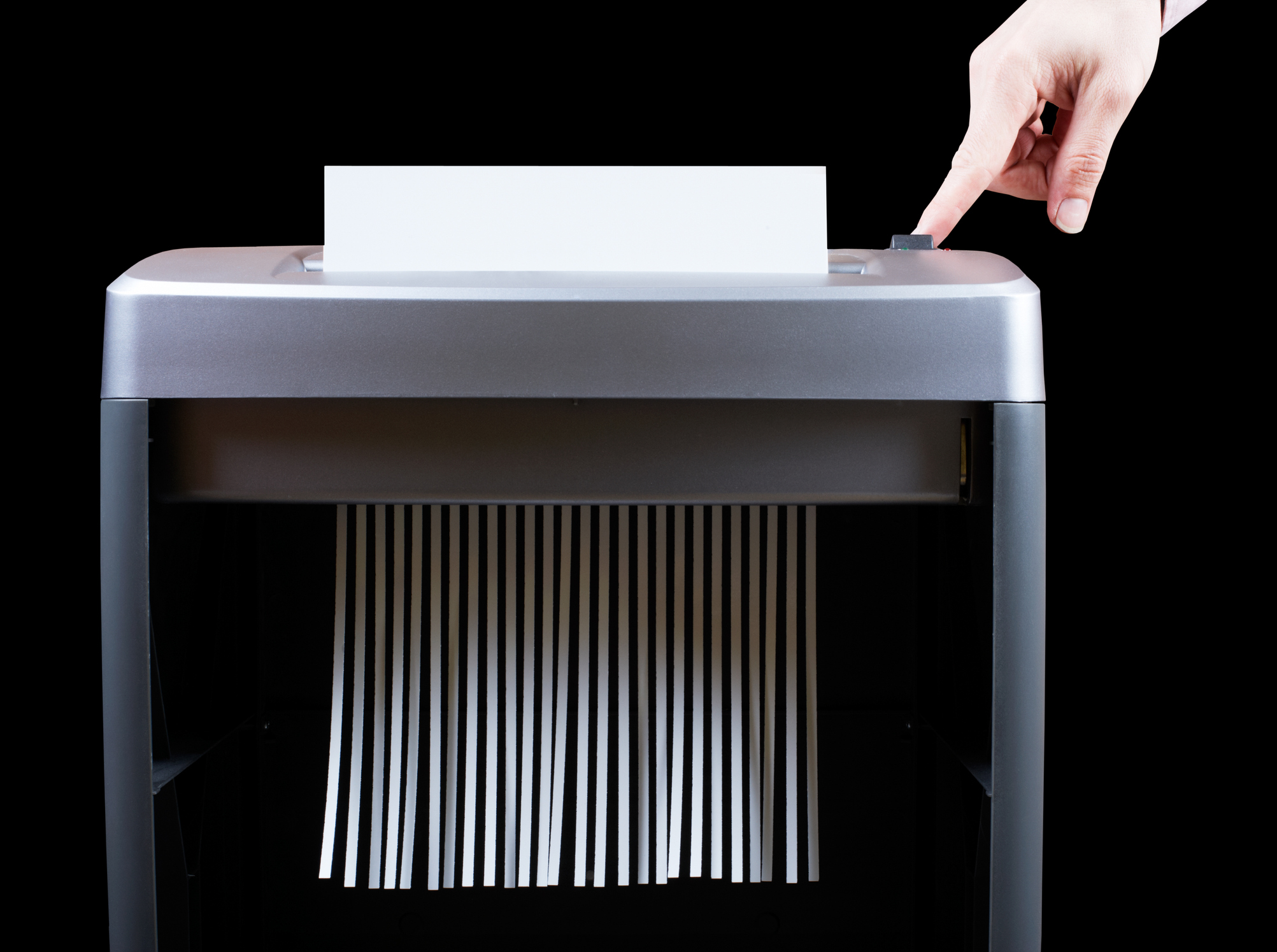 person pushing button on paper shredder