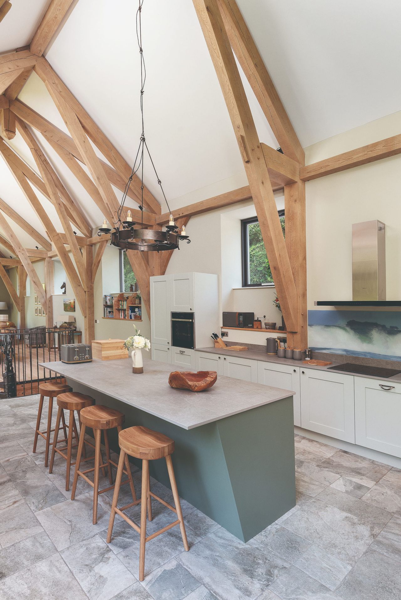 A contemporary barn conversion kitchen with a vaulted ceiling and stools at a kitchen island