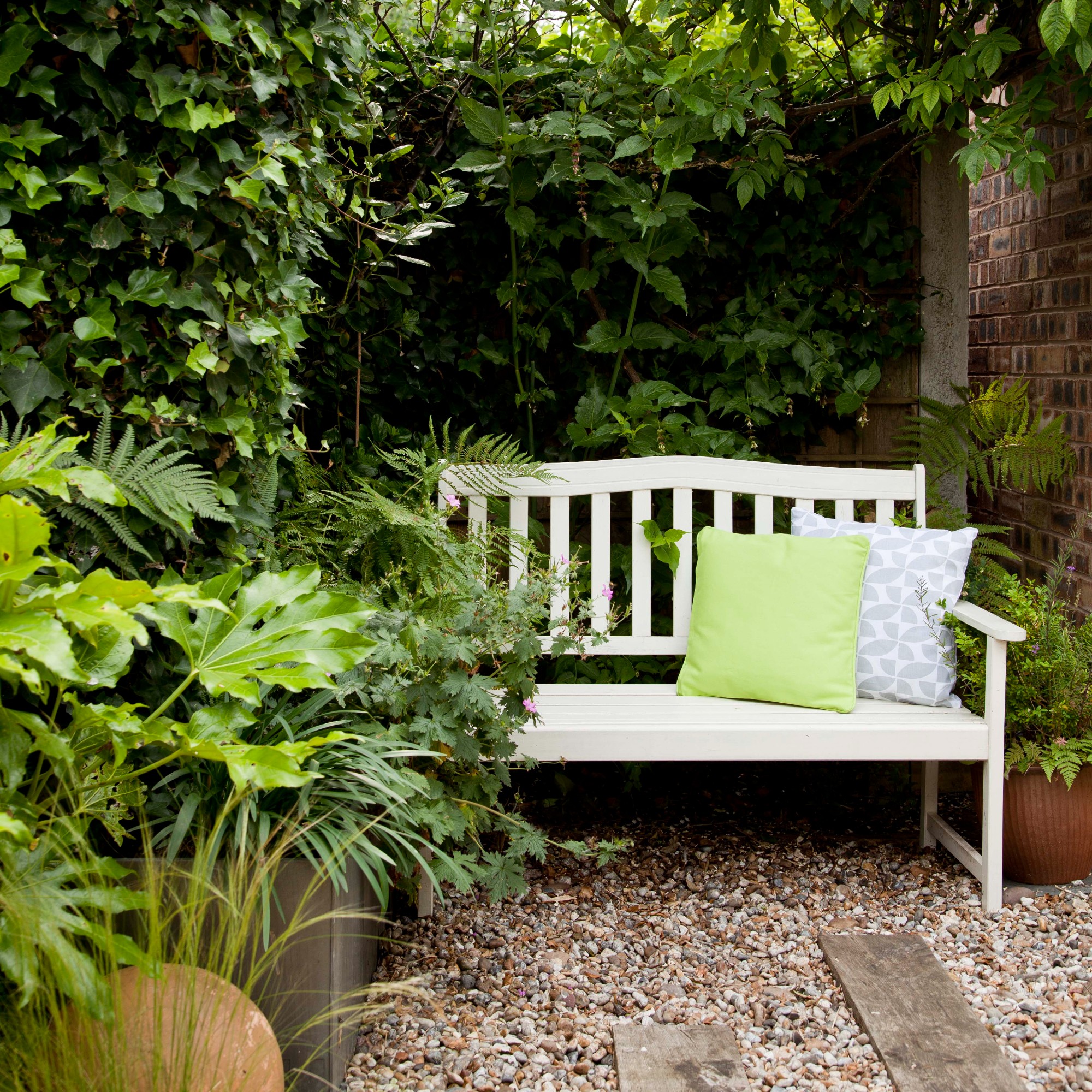 A garden with a white garden bench with cushions