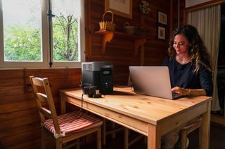 Portable power station in use on a wooden table to charge a laptop in cabin