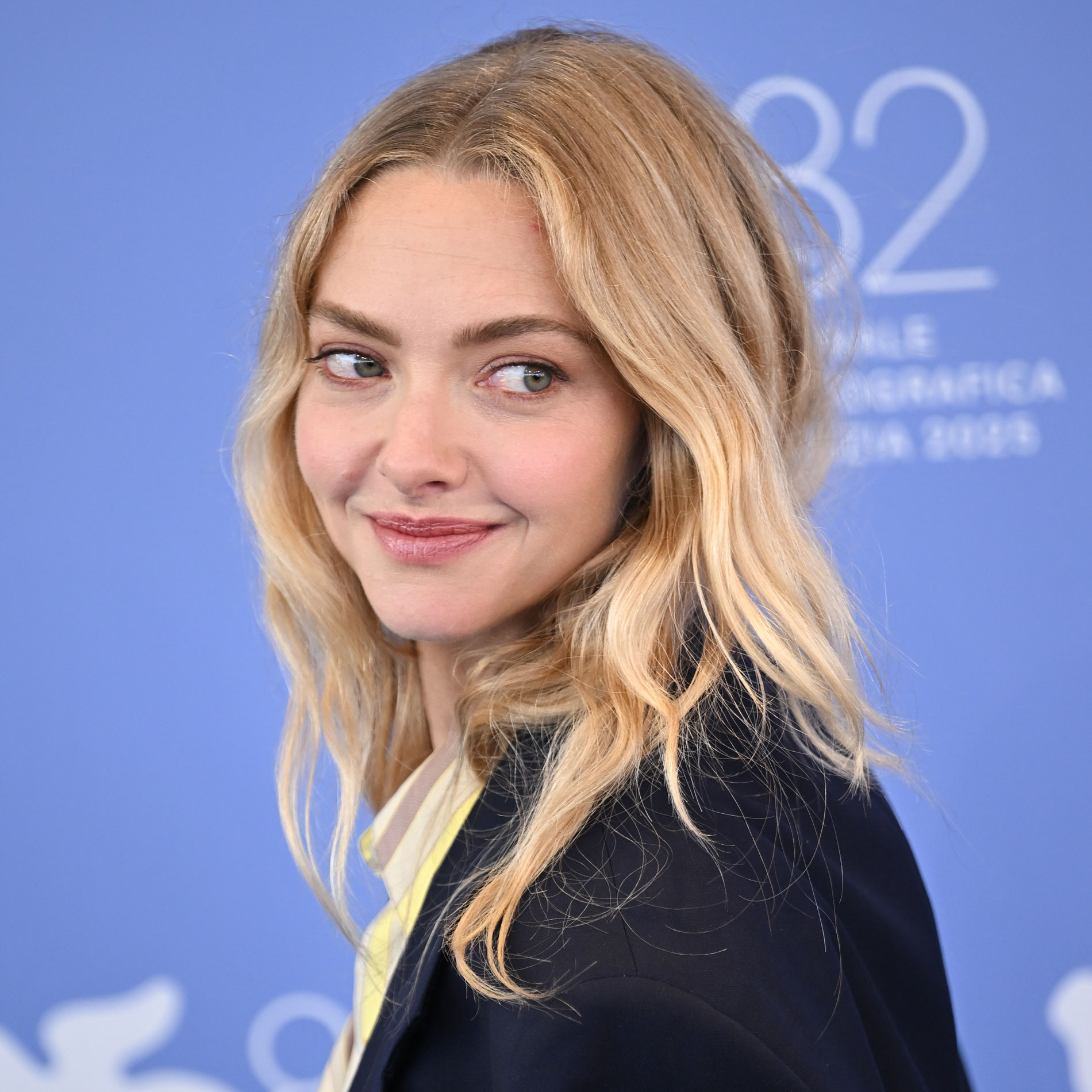 Amanda Seyfried looks over her shoulder wearing a blazer