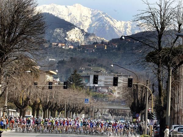 The peloton ride in the shadow of snow-capped peaks.