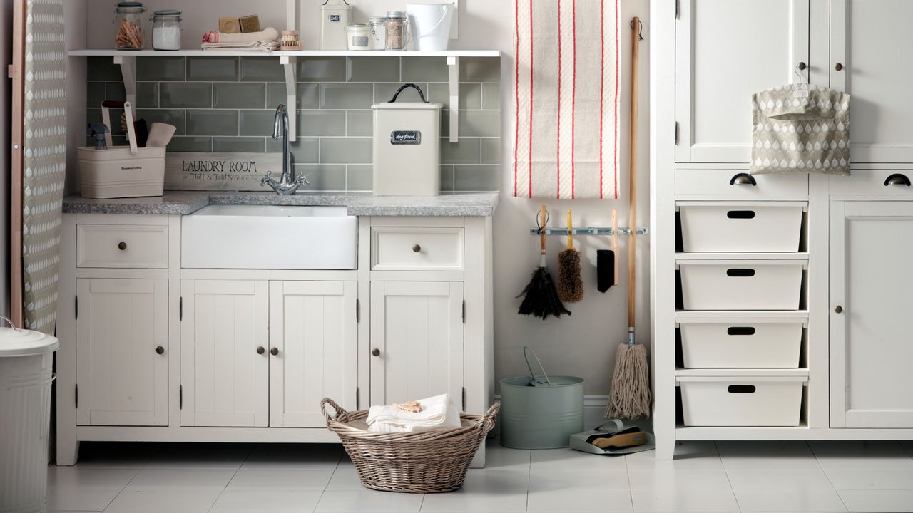 white and grey laundry room with basket of clothes, cleaning products and storage