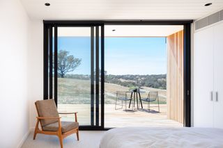 Bedroom with open glass panel door looking out to the view of the surrounding landscape