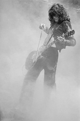 Jimmy Page onstage with violin bow, shrouded in dry ice