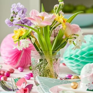 Decorative glass filled with bouquet of spring flowers on an easter table