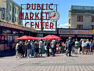 Tourists stand in front of the entrance to Pike Place Market in Seattle