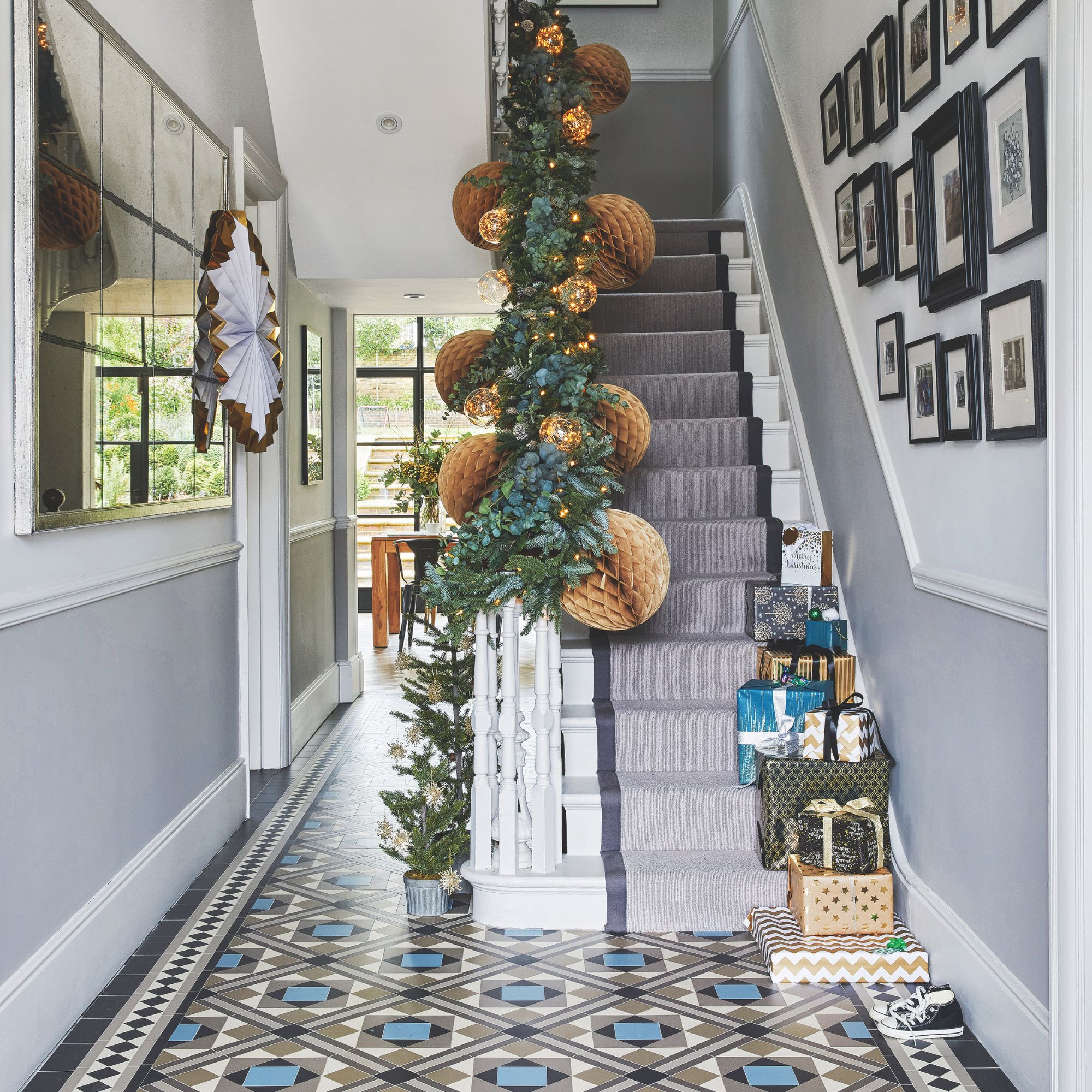 Hallway with colourful tiled floor and a staircase adorned with christmas decorations