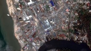 a satellite image of flattened buildings next to a flooded river