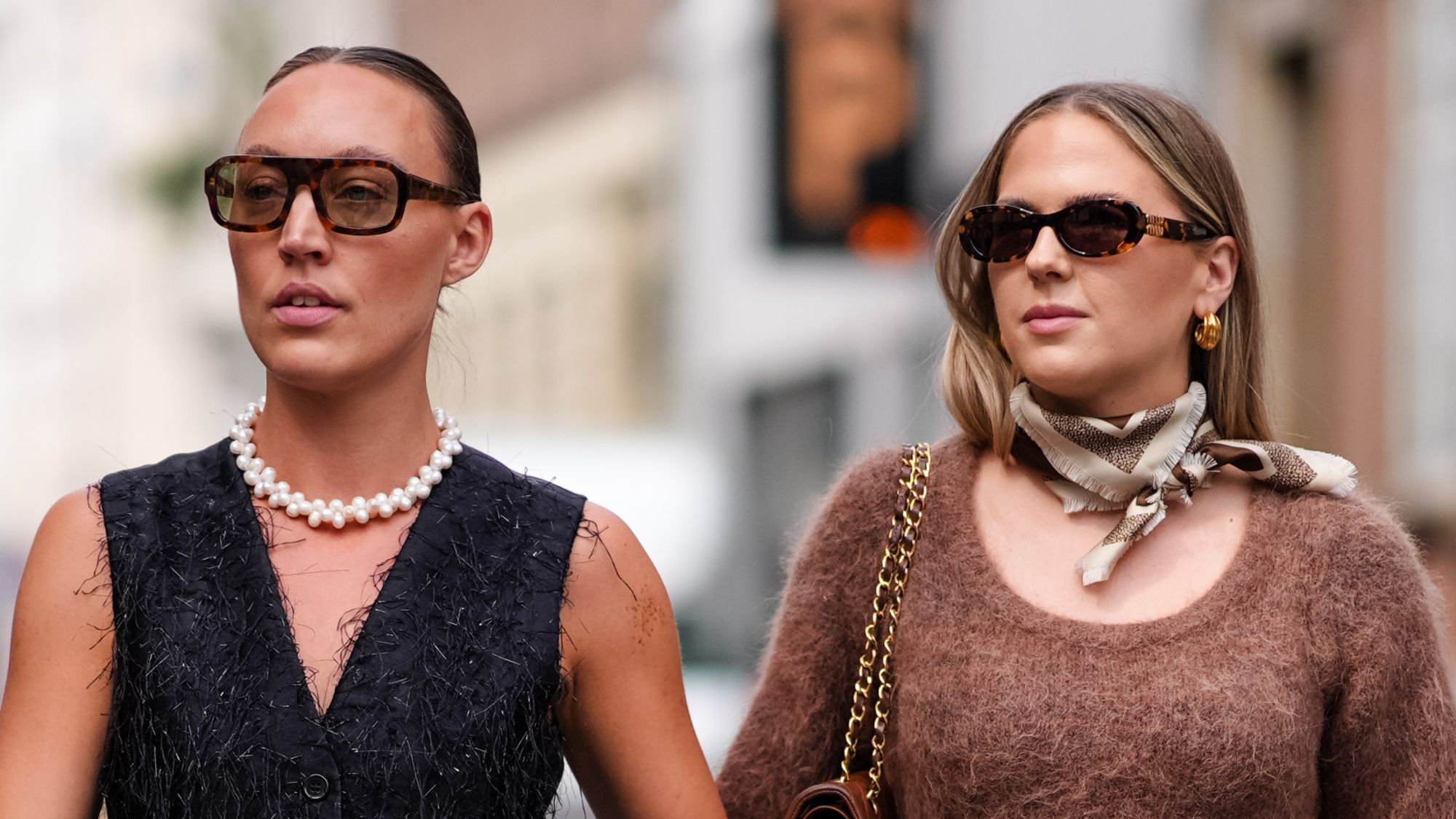two women walk down the street during copenhagen fashion week, both in sunglasses