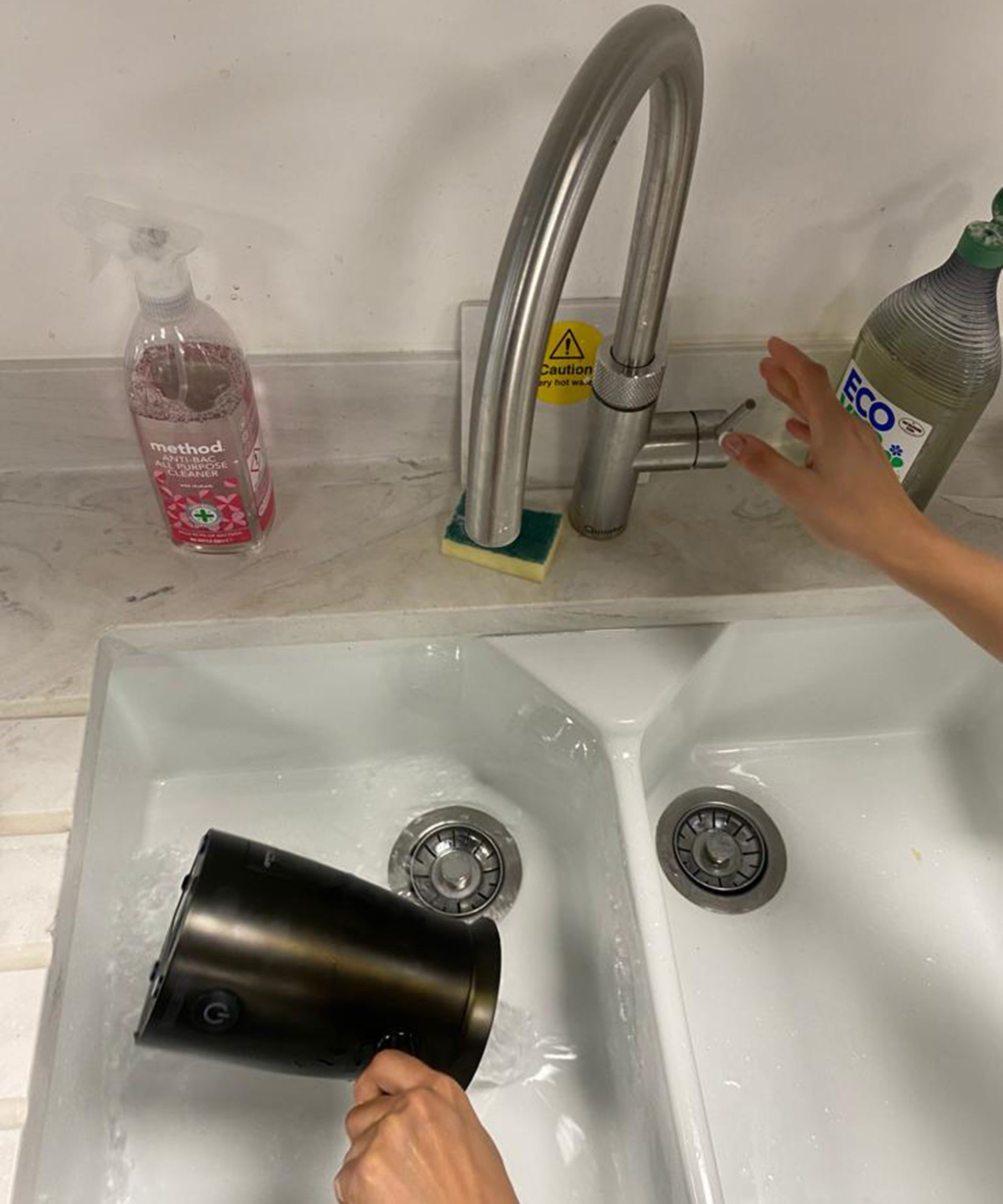 Christina Chrysostomou membilas buih susu dari Hotel Chocolat Velvetiser di wastafel