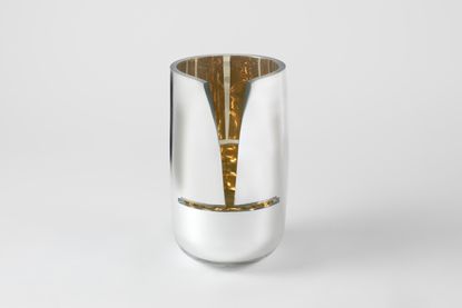 Silver mirrored vase with a cut at the front showing a golden inside.