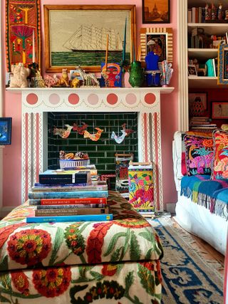 sitting room with colorful embroidered artwork hand decorated fireplace and bright cushions