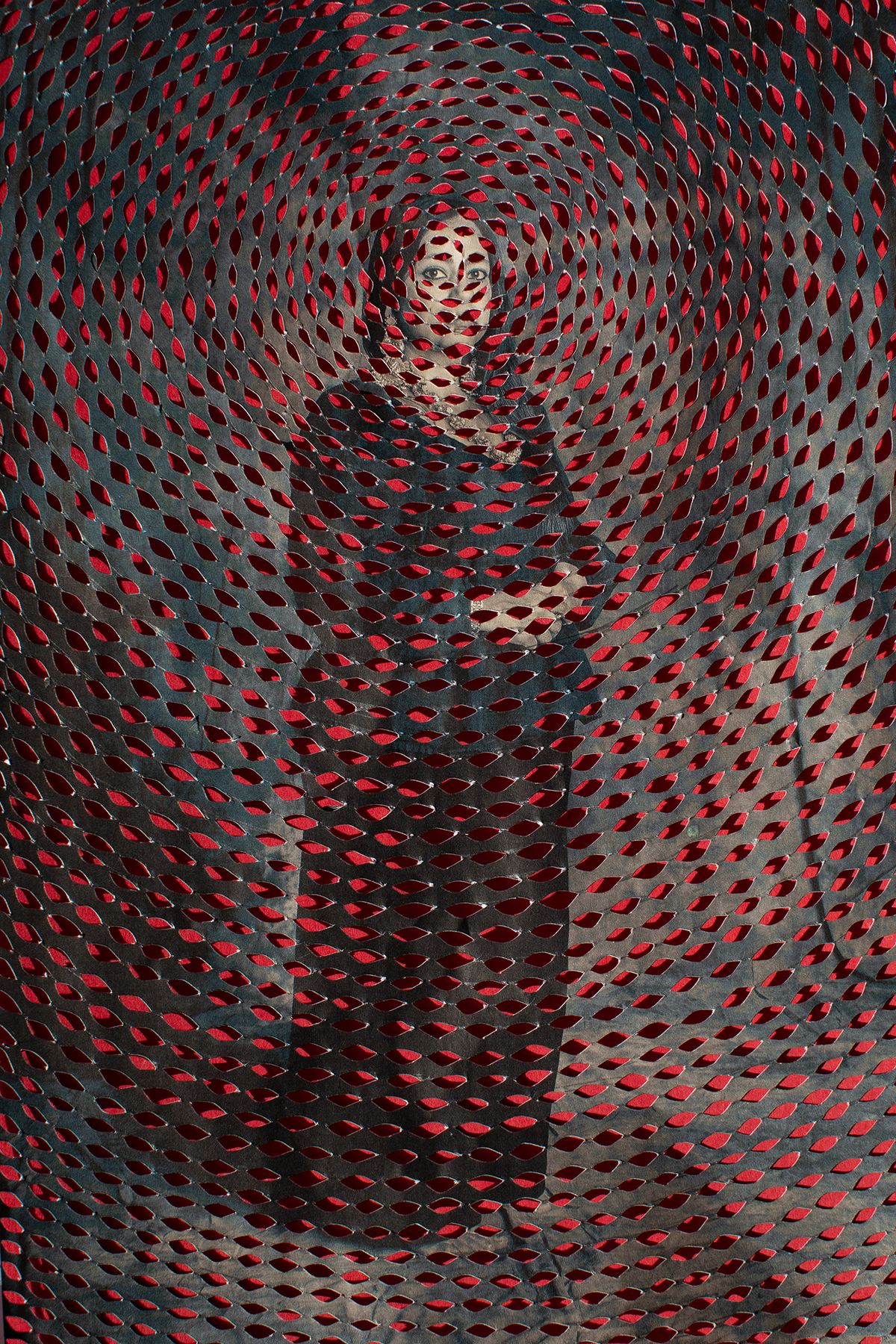 A woman standing in traditional attire, having her hands in front of her stomach, surrounded by intricate patterns