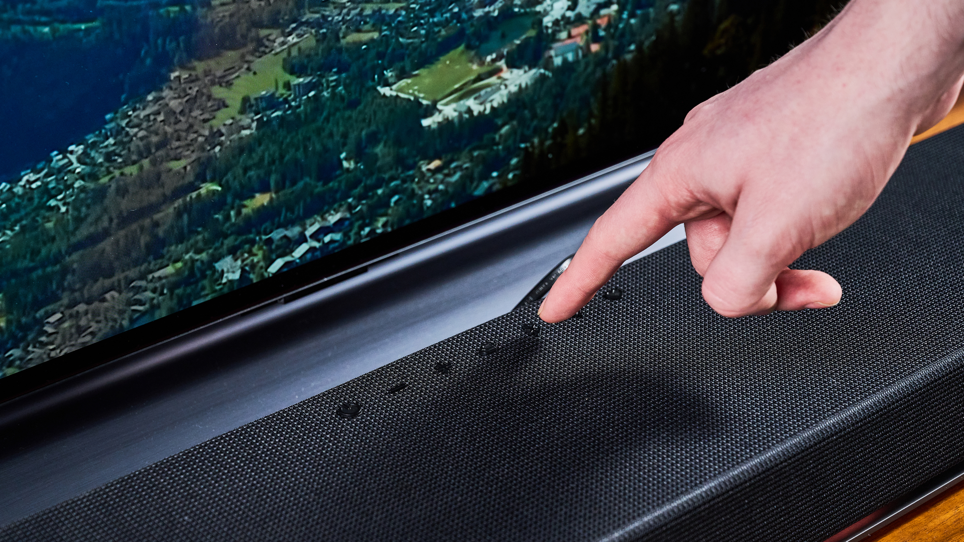 Man pressing button on LG Sound Suite H7 soundbar