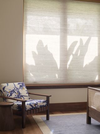 Fabric blinds in a bedroom with a floral, white and blue accent chair with wooden features