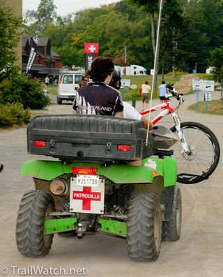 A First Aid Patrol shuttles a New Zealand rider and her bike to the medical center